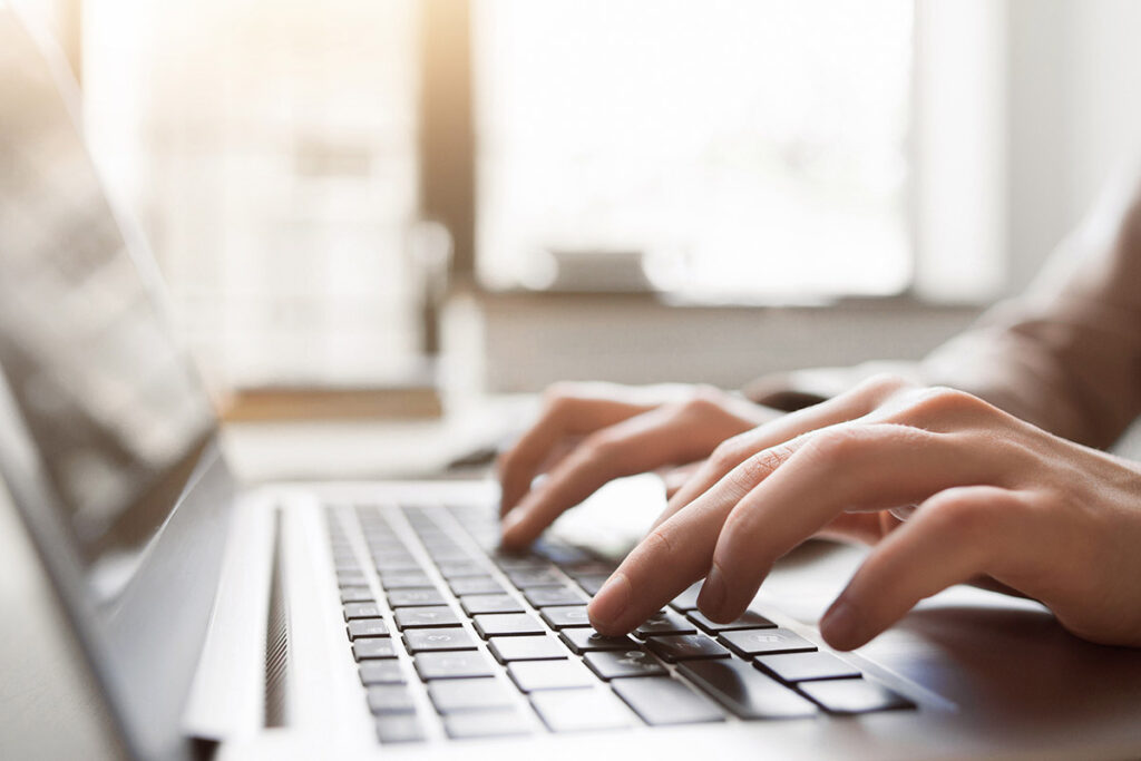 Hands typing on a laptop keyboard.