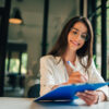 Smiling young woman filling application form or writing personal information in contract.