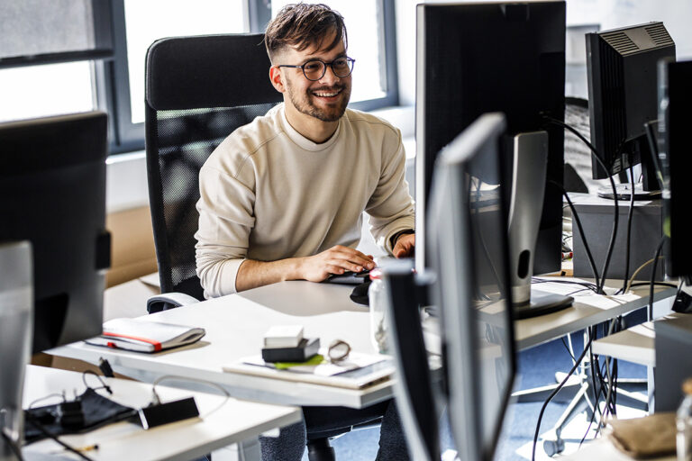 Young programmer sitting at the desk in his office and working.